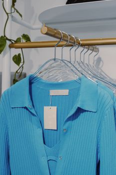 Stylish blue ribbed garments hang neatly on gold racks in a chic boutique setting.
