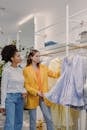 Woman in Yellow Blazer Standing Beside Woman in White Long Sleeve Shirt