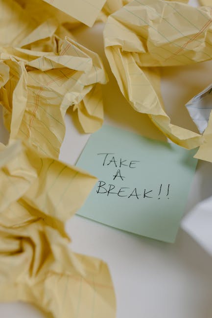 Close-up of a sticky note with 'Take a Break' surrounded by crumpled papers, suggesting a pause.