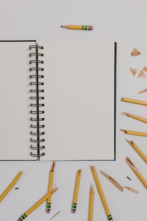 Black Notepad surrounded with Broken Pencils 