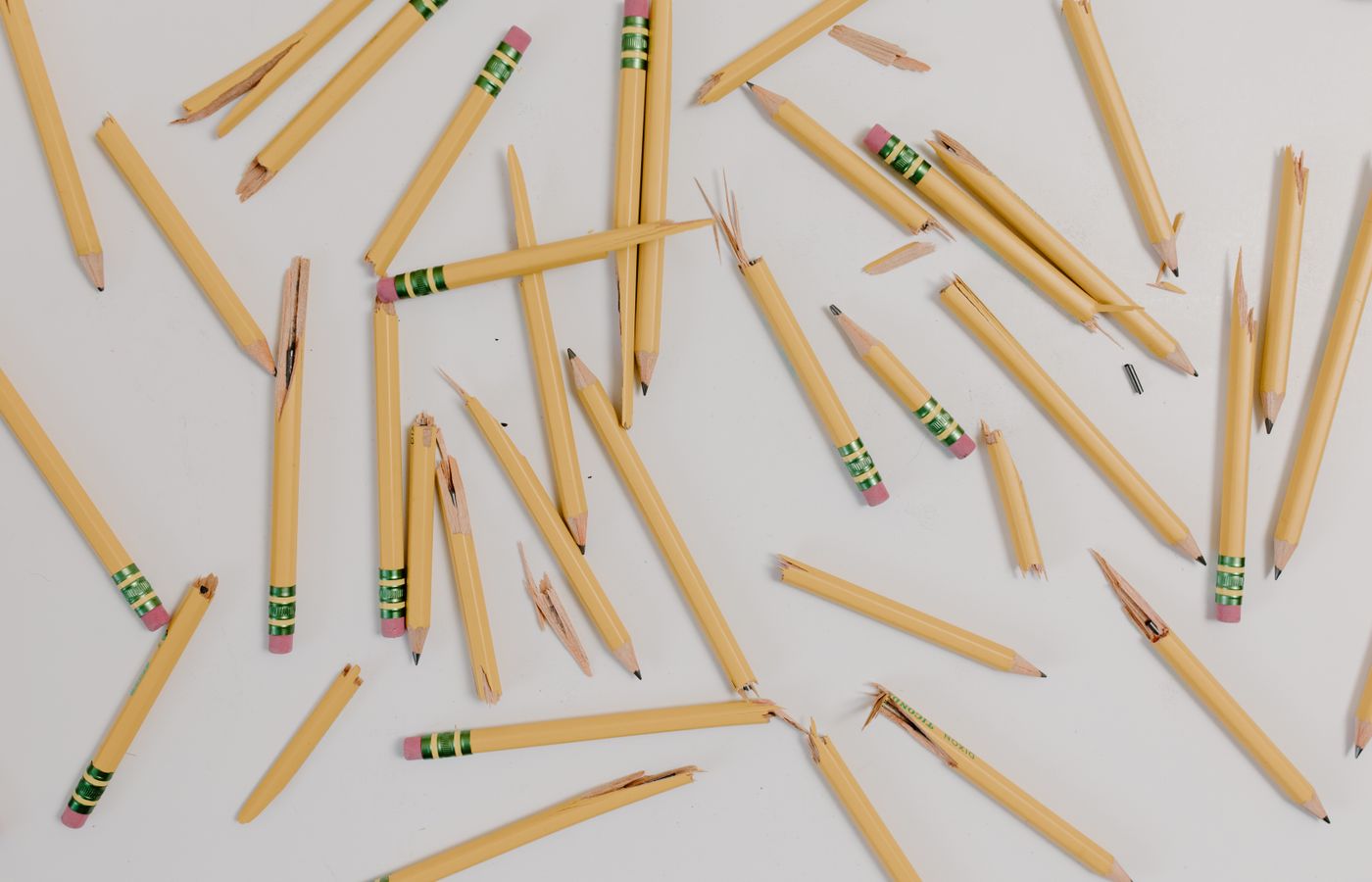 A flat lay of broken pencils scattered on a white background.