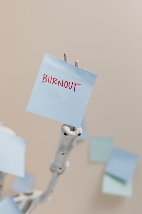 Free A skeleton holding a sticky note reading 'Burnout', symbolizing workplace stress. Stock Photo