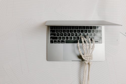 Overhead Shot of a Skeleton Hand Typing on a Laptop