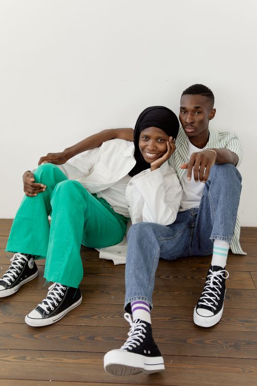 Free Happy couple sitting on a wooden floor, embracing and smiling indoors. Stock Photo