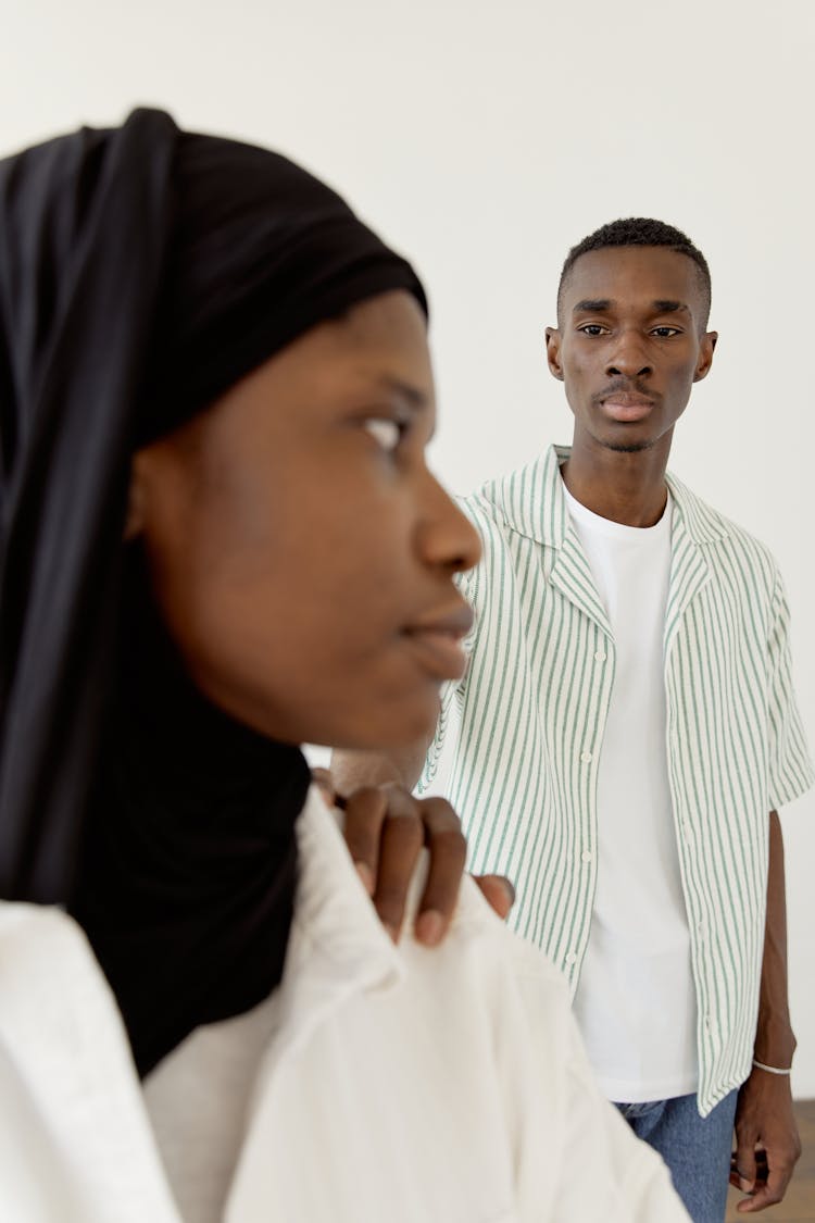 Man In Striped Polo And White Shirt Touching Woman's Shoulder