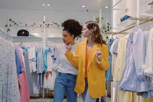Two stylish women explore a trendy clothing boutique, showcasing vibrant fashion choices.