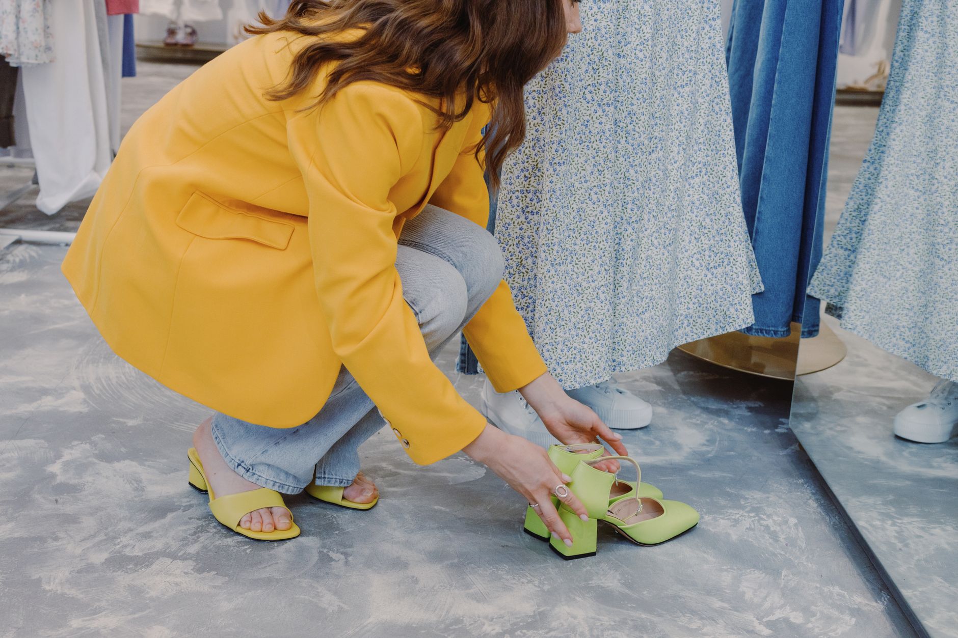 Stylish woman trying on vibrant shoes in a modern department store. (Photo by Ron Lach on Pexels)