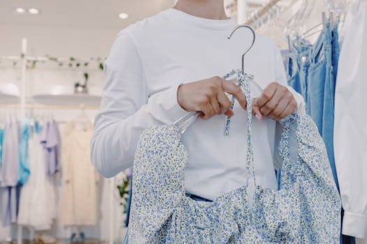 A woman in a clothing store selecting a floral dress, showcasing modern women's fashion.