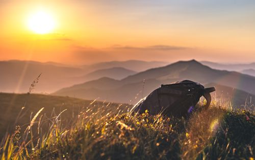 Free Captivating sunset over Polish hills, featuring a backpack on a grassy field, ideal for travel inspiration. Stock Photo