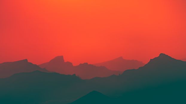 Beautiful silhouette of Tenerife mountains at sunset with vibrant orange sky, capturing serene nature scene.