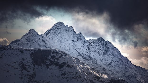 A stunning view of snowy mountain peaks under a dramatic cloudy sky in Italy during winter.
