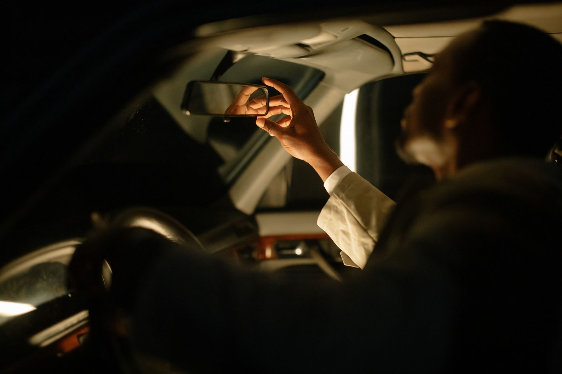 Driver adjusting a vehicle mirror inside a modern car