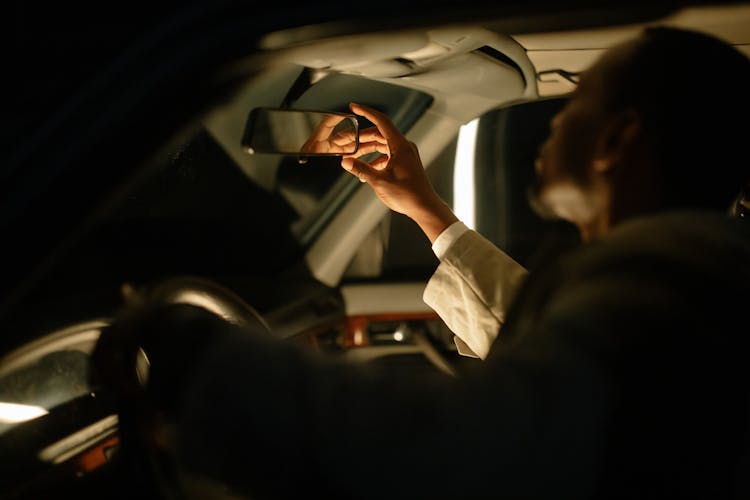 Man Sitting Inside A Car Fixing The Rear View Mirror