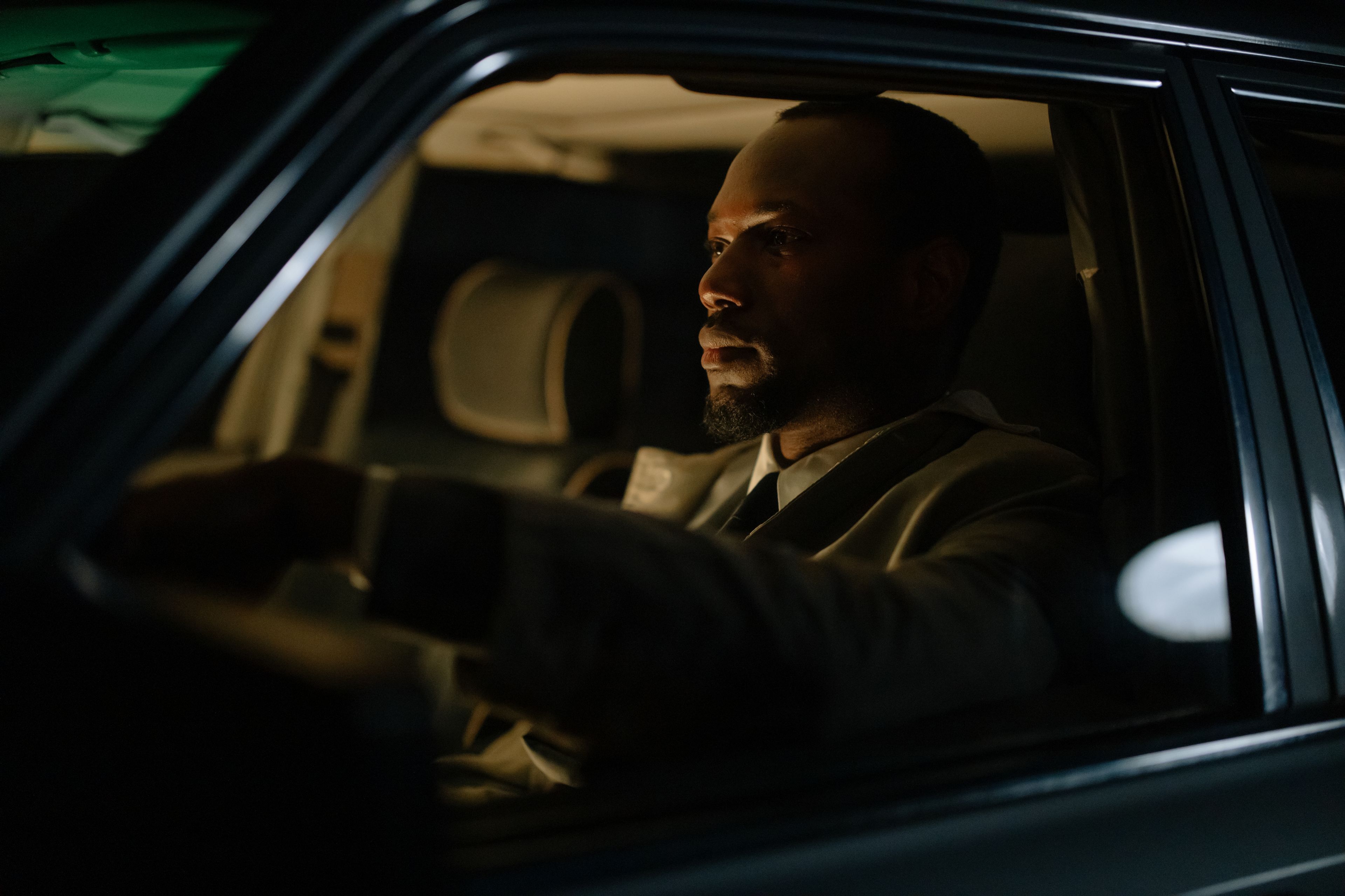 A professional chauffeur waiting beside a luxury car