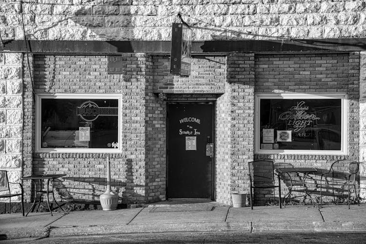 Grayscale Photo Of A Storefront With Stonewall And Glass Windows