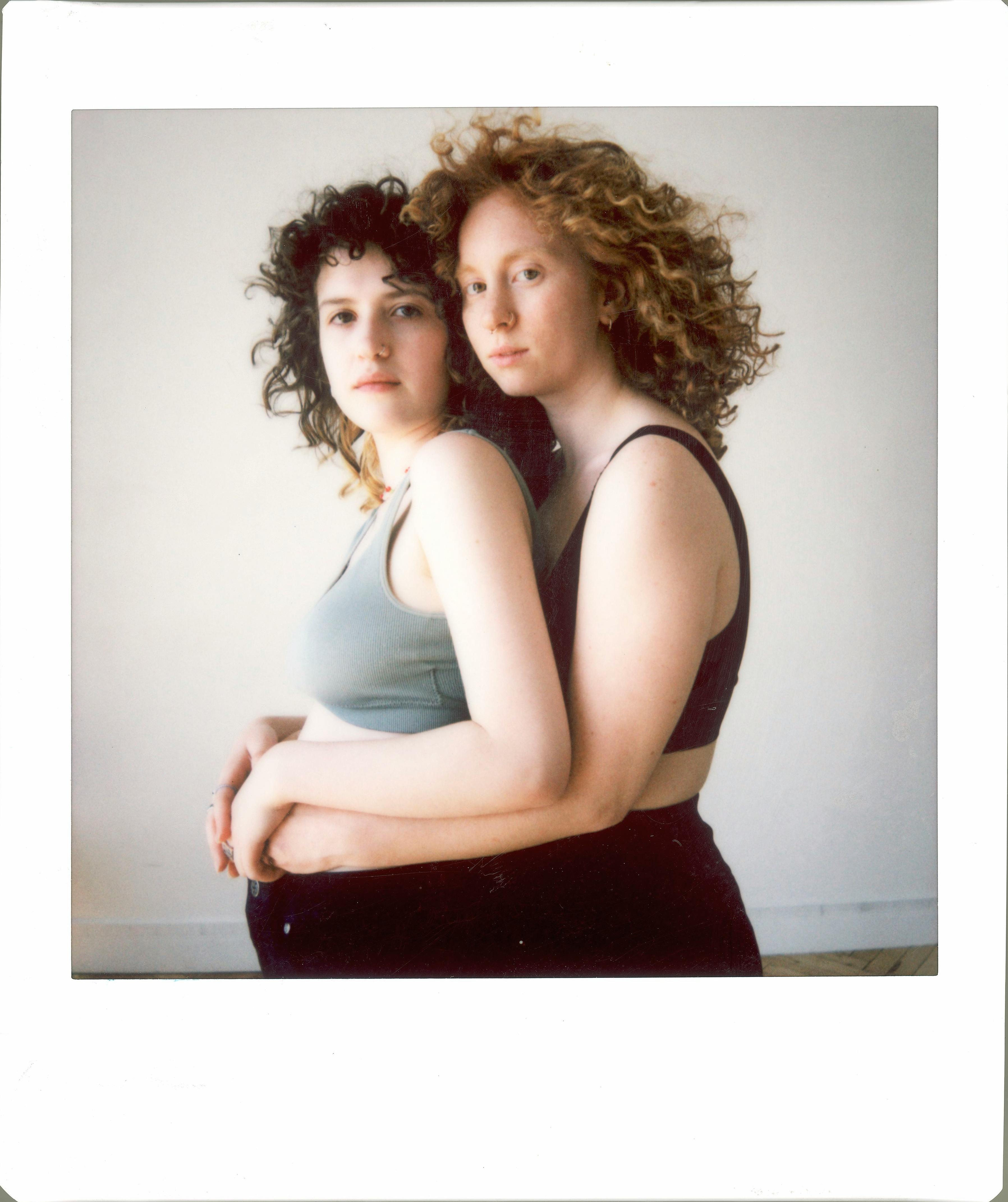 A touching portrait of two women embracing in tank tops, conveying warmth and connection.