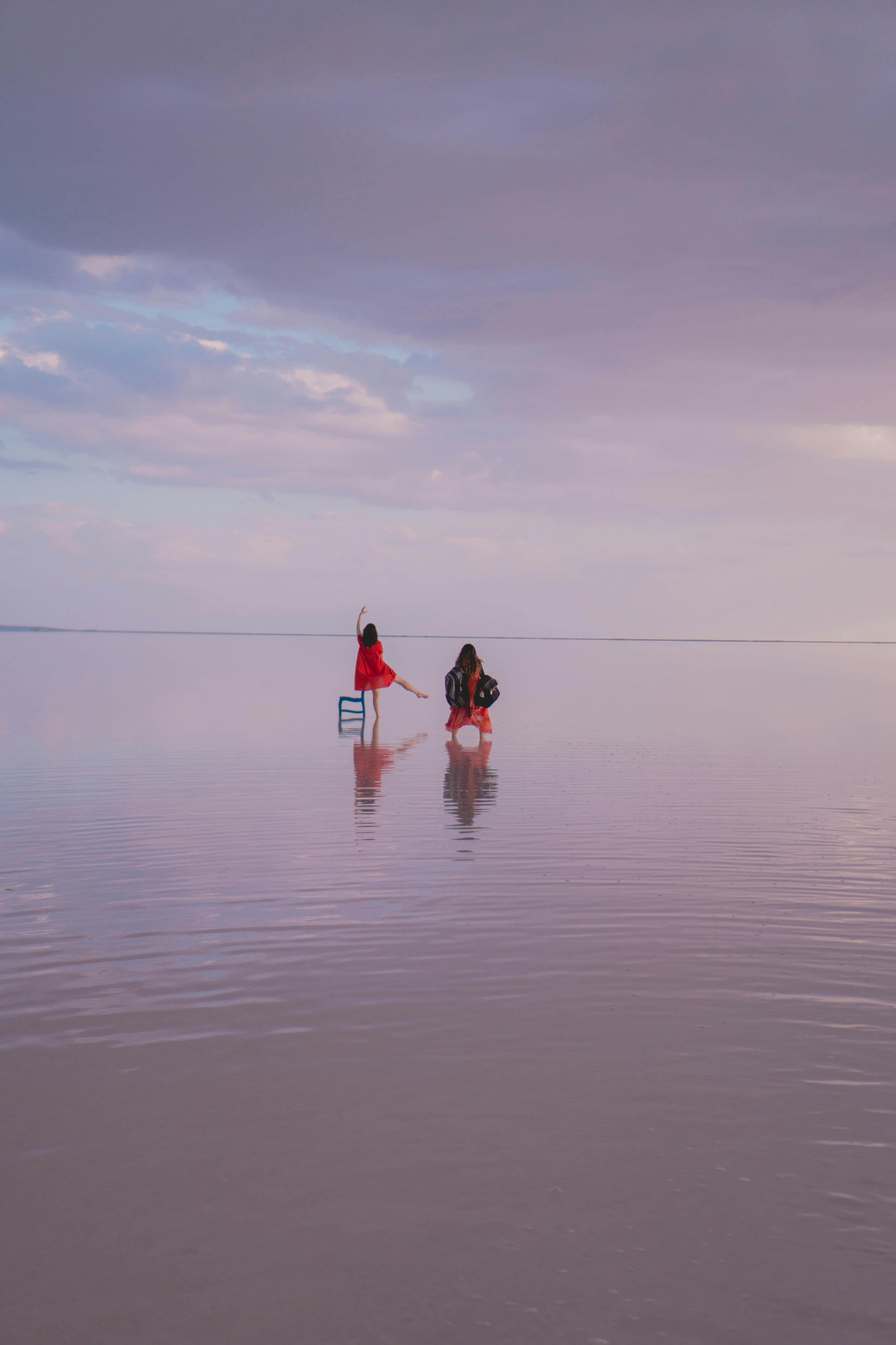 Two dancers perform gracefully on a reflective surface with a serene sea and colorful sky backdrop.