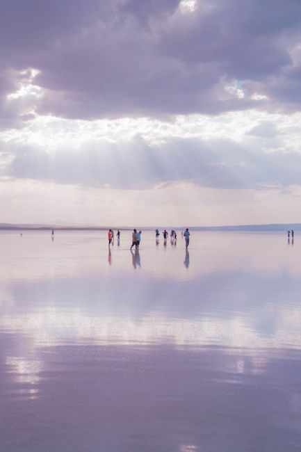 Captivating scene of people reflected on a calm ocean surface under a dramatic cloudy sky.