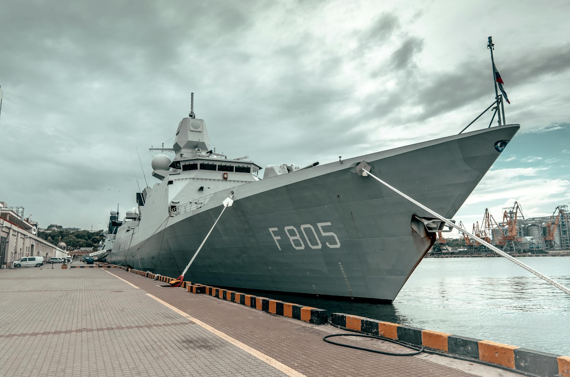 A large naval ship docked in Odessa harbor under a cloudy sky, showcasing maritime strength.