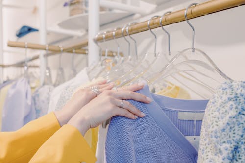 Free Person in Yellow Long Sleeve Shirt Holding Clothes with Hangers Stock Photo