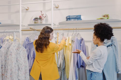 Woman in Yellow Long Sleeve Shirt Standing Beside White and Blue Floral Dress Shirt