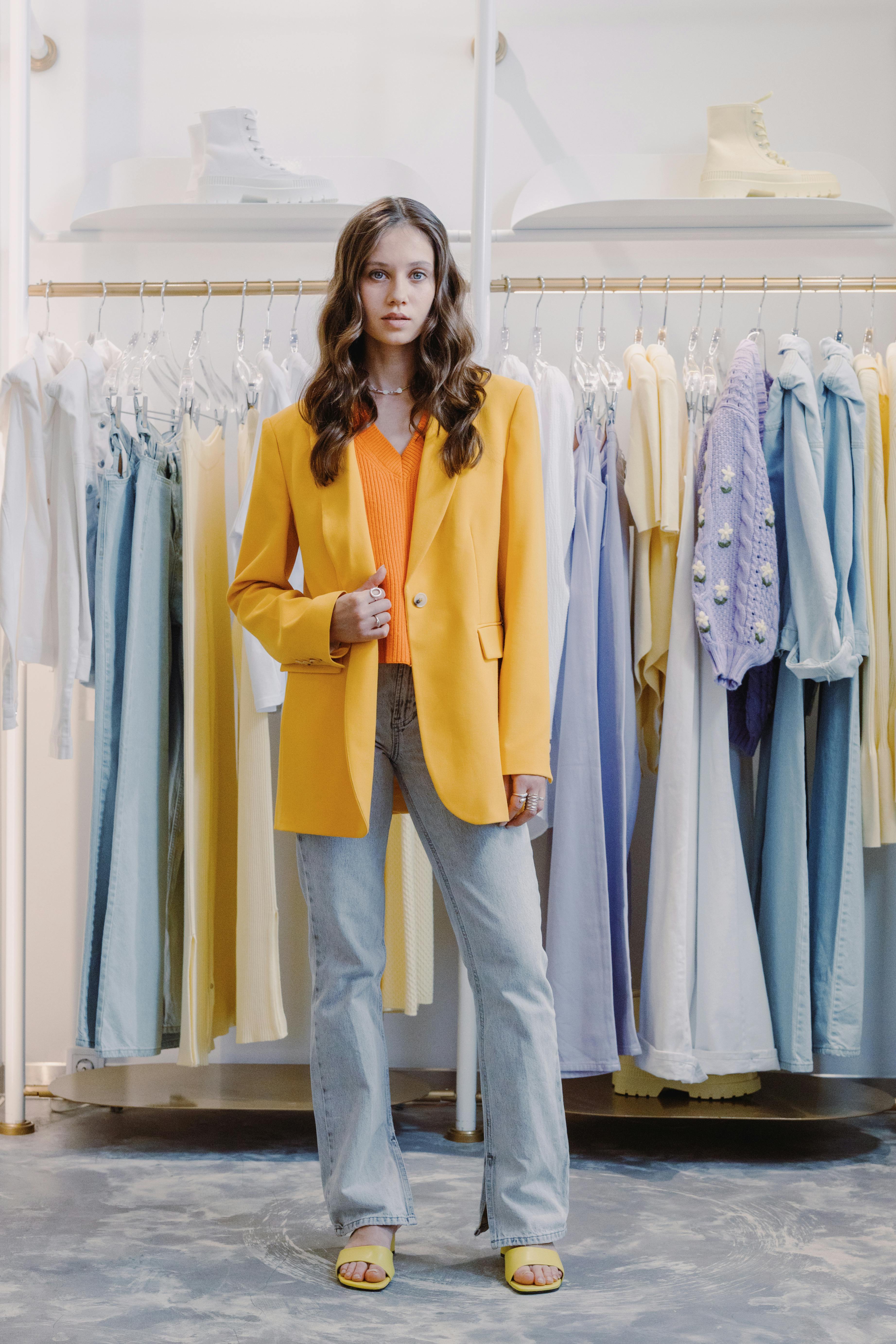 woman in yellow blazer standing beside clothing rack