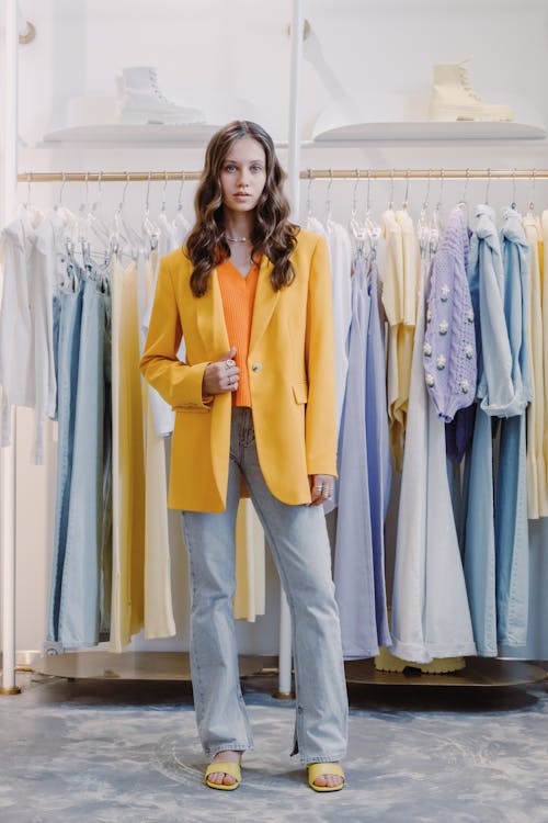 Woman in Yellow Blazer Standing Beside Clothing Rack