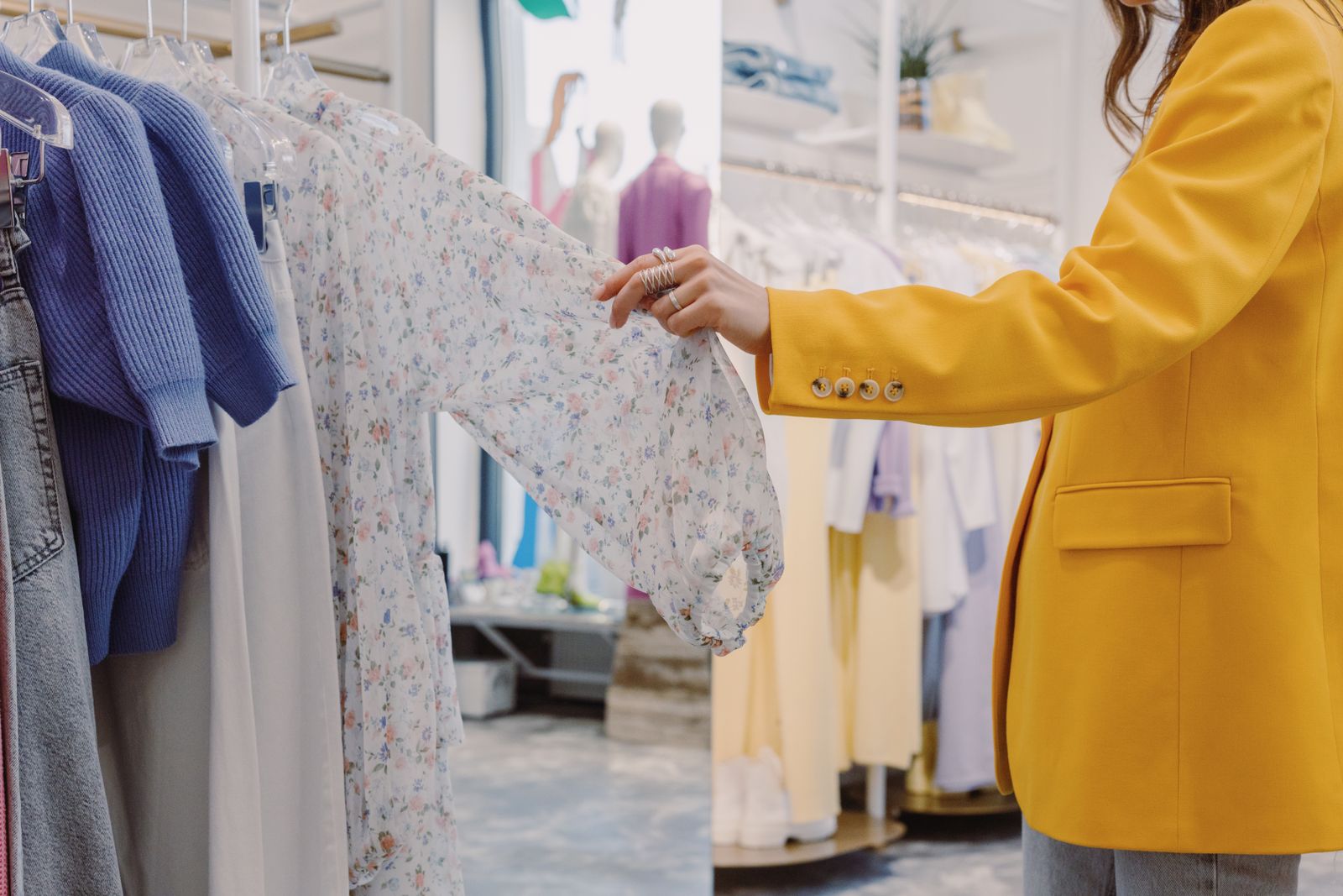 A woman considering a dress in a fashion boutique. Photograph by Ron Lach via Pexels.