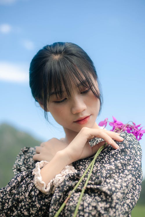 Close Up Photo of Woman Holding Purple Flowers