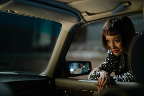 Free Woman Holding a Cigarette Leaning on a Car Window Stock Photo