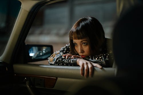 Woman in Black Leather Jacket Leaning on a Vehicle Window