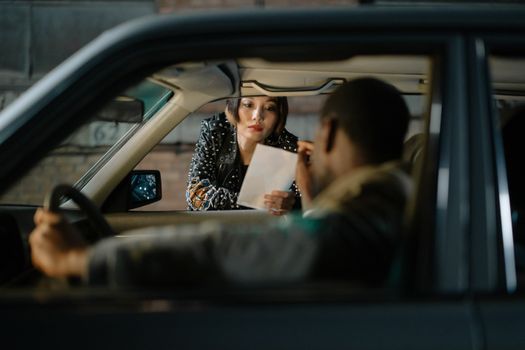 Woman Holding a Paper Beside a Car Window
