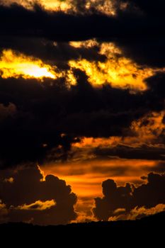 Vivid sunset with striking silhouettes of dark clouds against a golden evening sky.