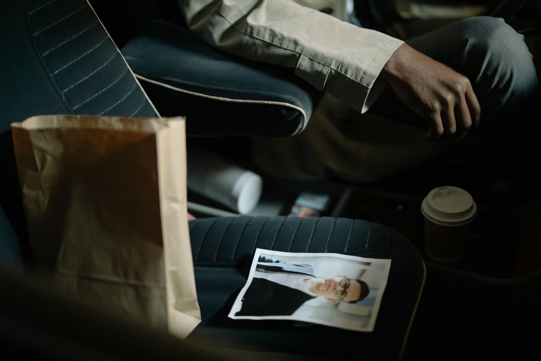 Close-up of car interior with photo, coffee cup, and paper bag, creating a suspenseful mood.