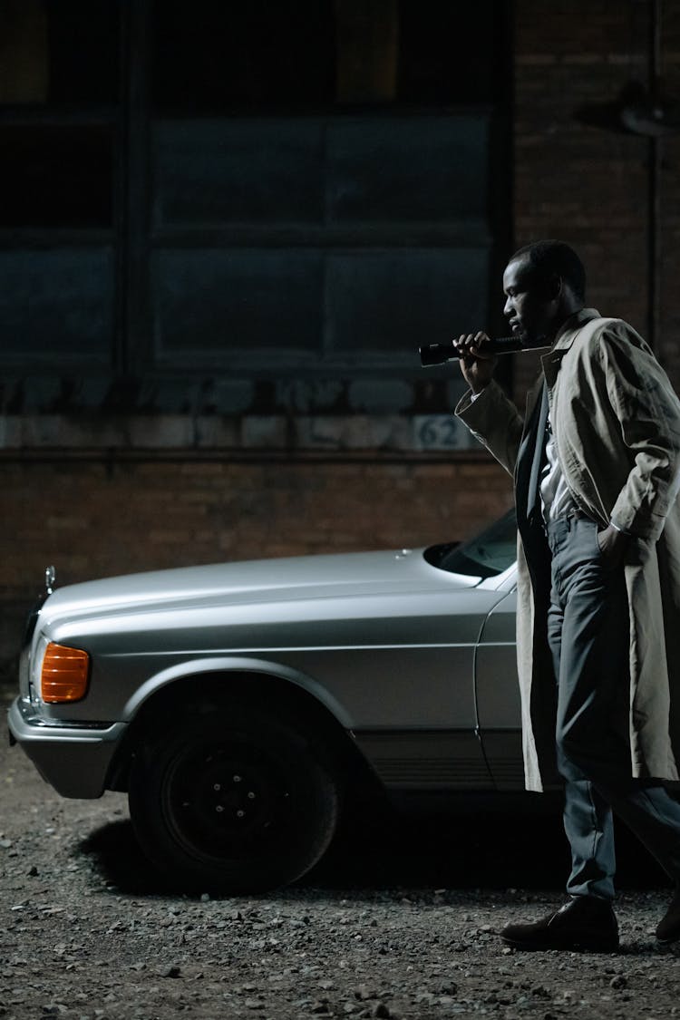 Man Wearing A Coat Standing Beside A Car