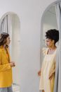 Woman in Yellow Blazer Looking at a Woman Wearing a Dress