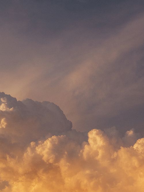 Free A serene cloudscape with fluffy clouds and pastel colors illuminated by the sunset. Stock Photo