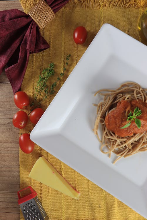 Pasta With Basil Garnish on White Plate Beside Tomatoes 