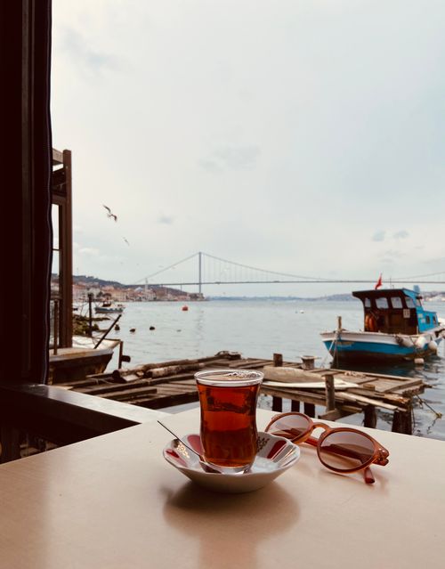 Free Tea cup on table with view of harbor and bridge, perfect coastal relaxation. Stock Photo