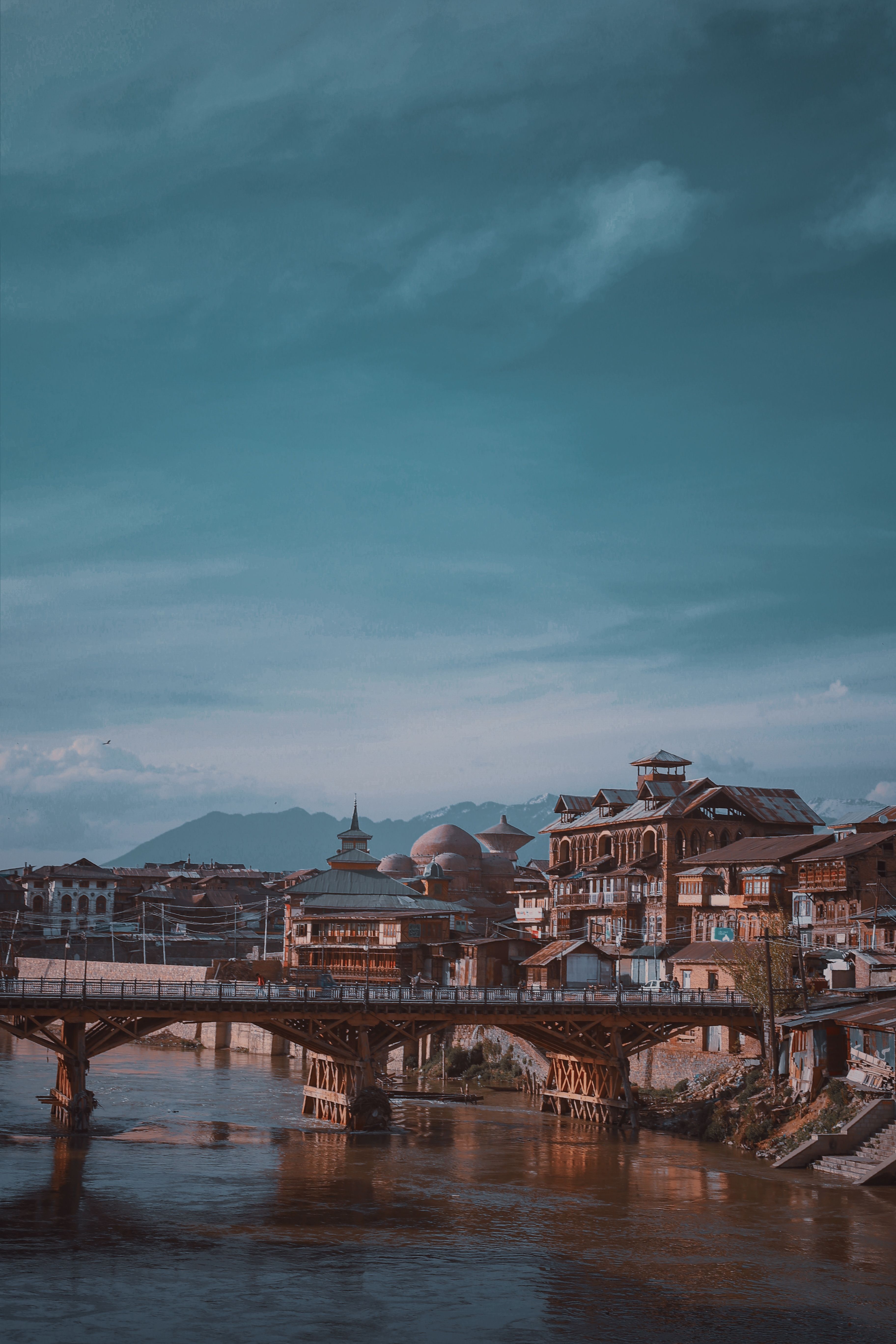 Stunning view of a traditional wooden bridge over a river amidst historic architecture under a blue sky.