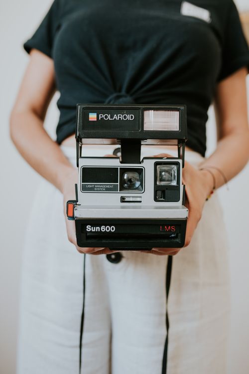 Free A woman holding a classic Polaroid Sun 600 camera in a close-up shot. Stock Photo
