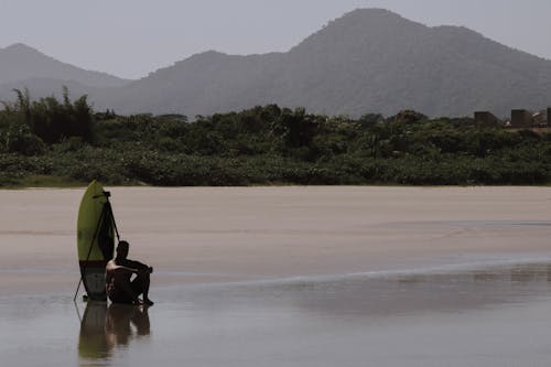 A Man Sitting on the Beach Sand