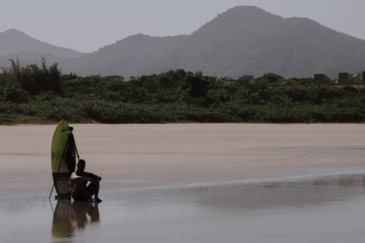 A Man Sitting On The Beach Sand