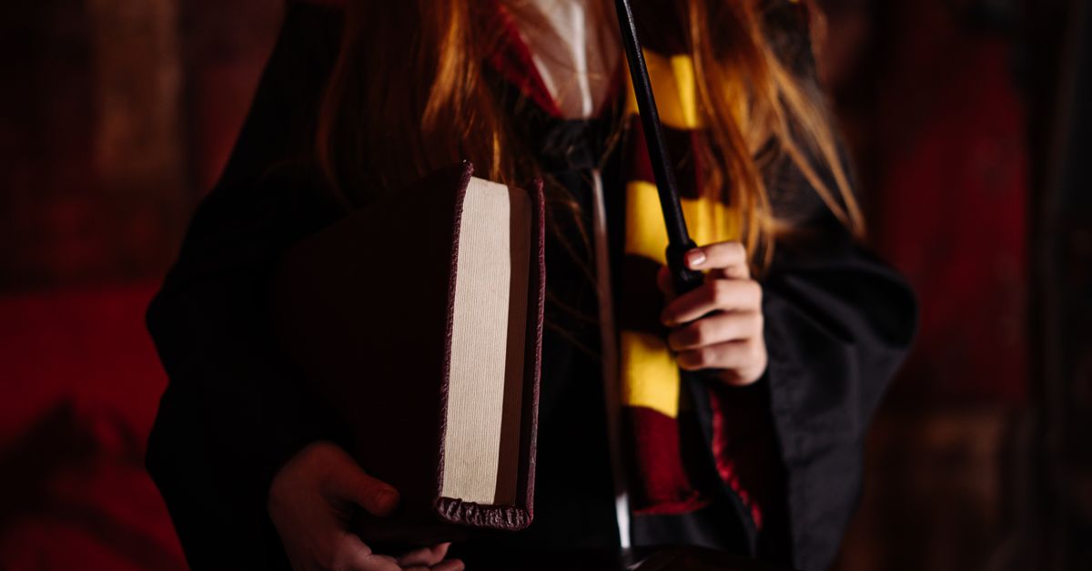 A girl in a wizard costume holding a wand and book, evoking magical themes.