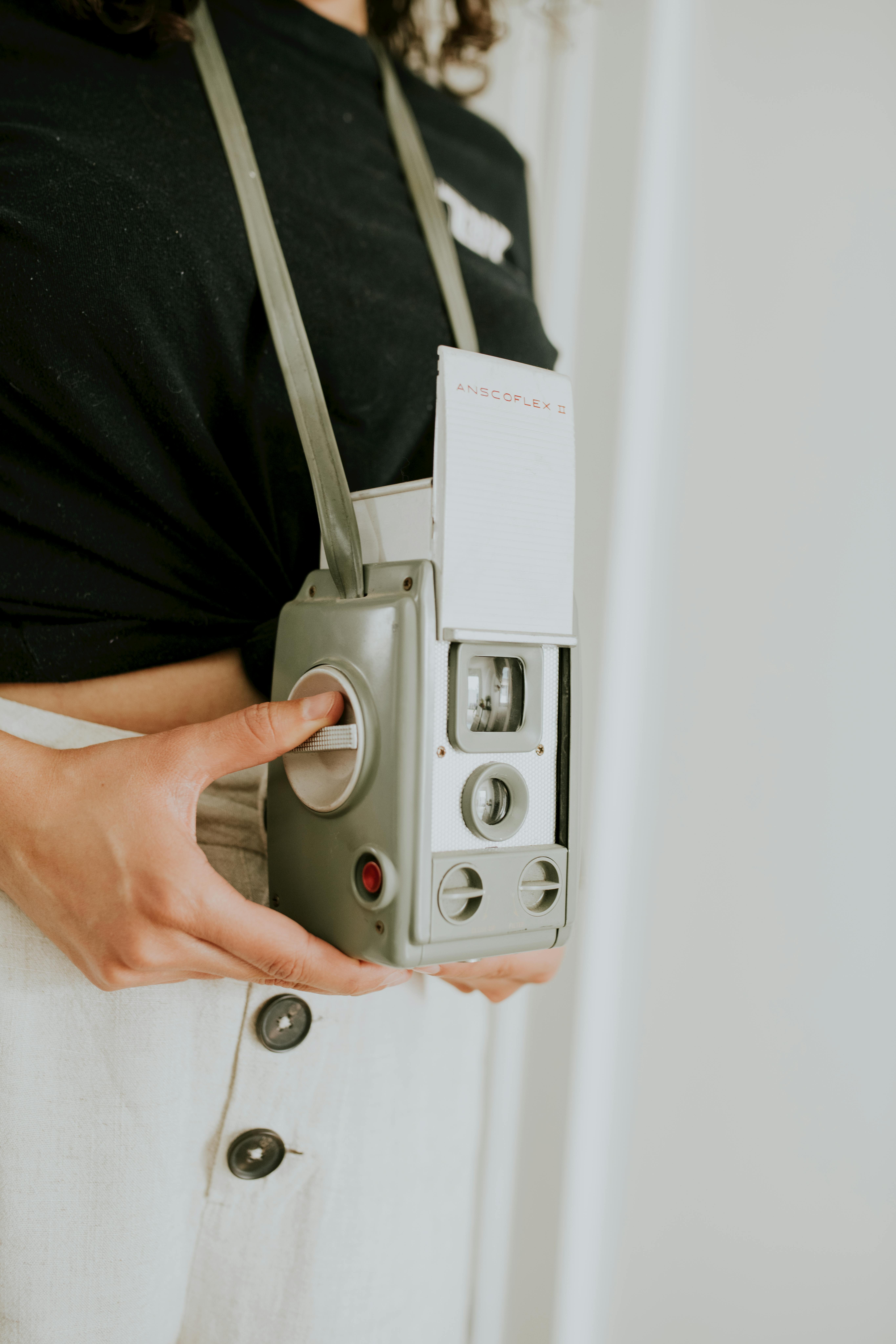 Close-up of a classic vintage camera held by a person, showcasing retro design.