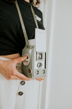 Close-up of a classic vintage camera held by a person, showcasing retro design.