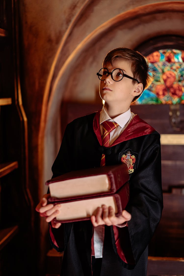 A Boy In Harry Potter Costume Carrying Books