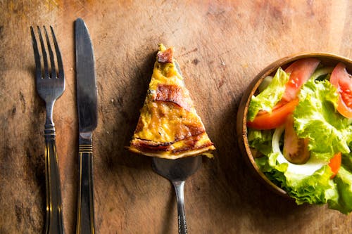 Free Slice of Pizza Beside Fork and Knife Stock Photo