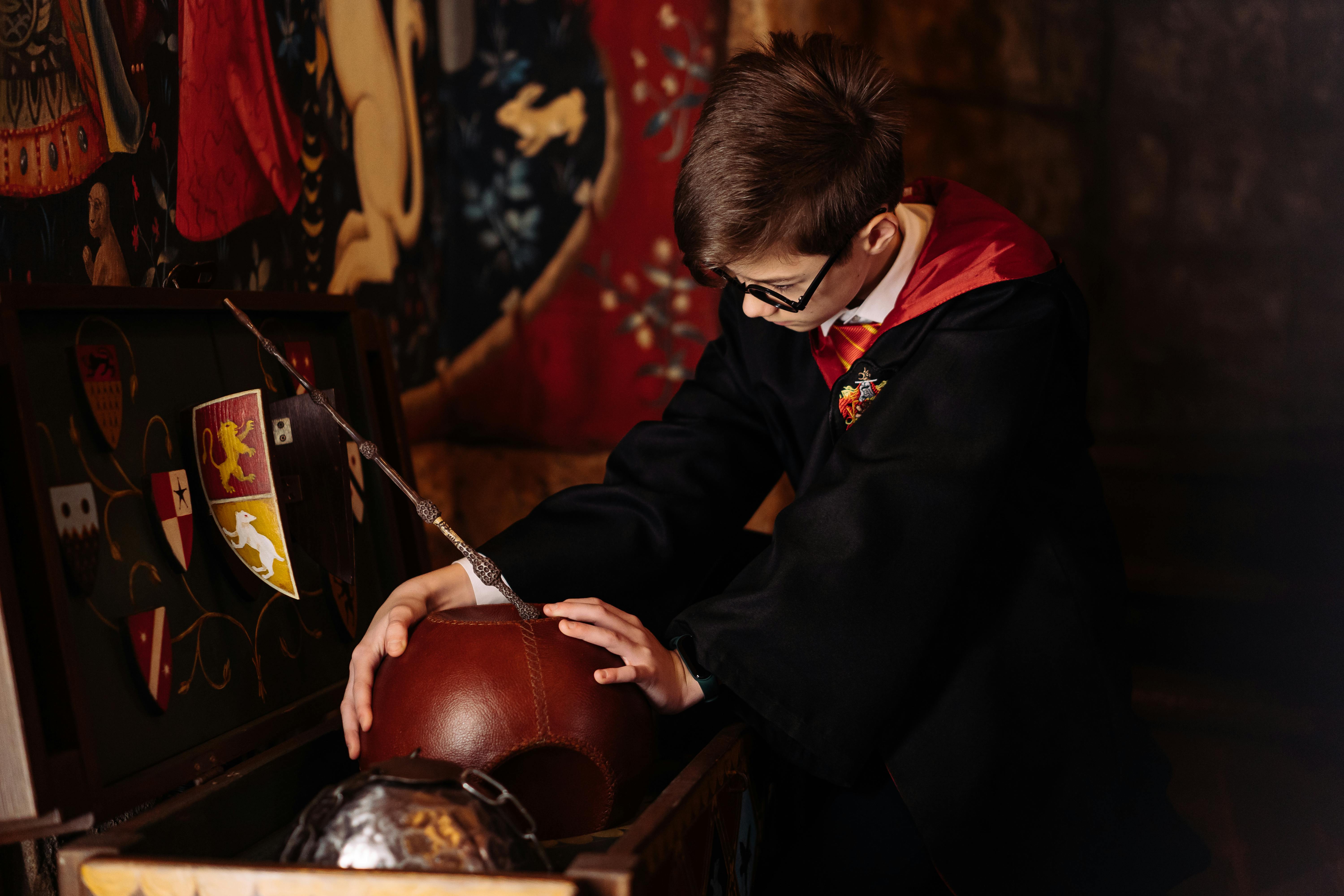 a boy wearing robe holding a ball from the wooden box