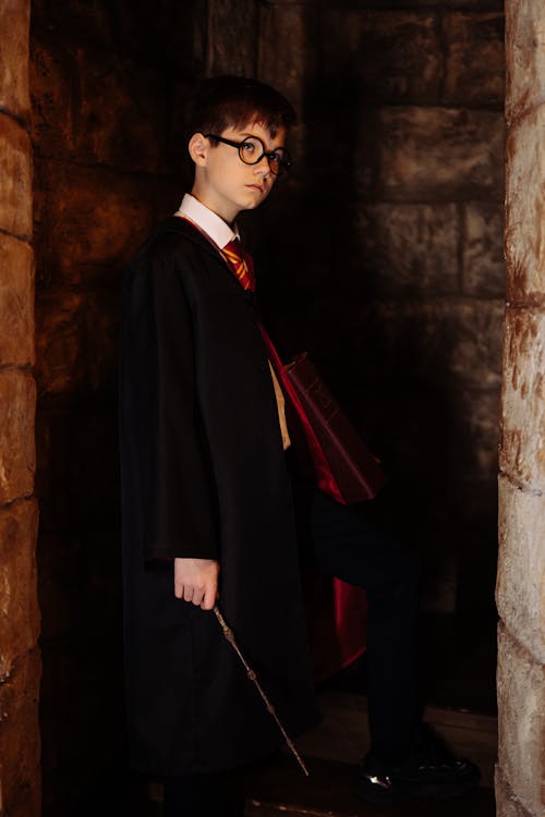 Teenage Boy Standing in a Harry Potter Black Robe Holding a Magic Wand